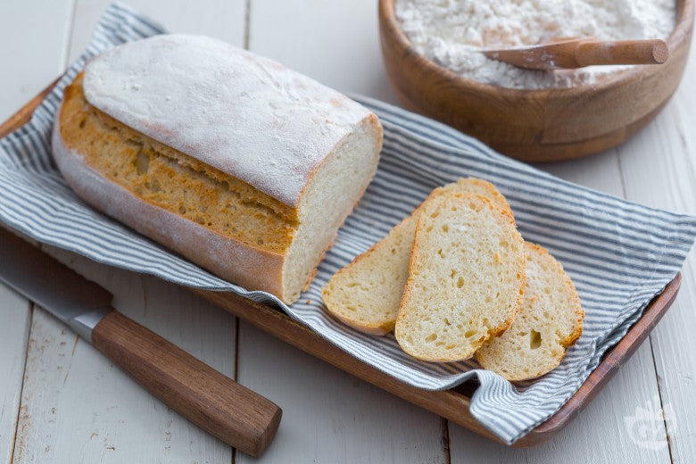 Filone di pane a lievitazione naturale con alcune fette tagliate, appoggiato su una griglia